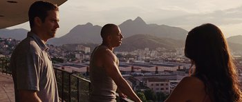 Movie still from “Fast Five” (2011), directed by Justin Lin – A man standing on a balcony looking out over a city; Medium shot, Over the shoulder angle