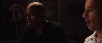 Movie still from “Fast Five” (2011), directed by Justin Lin – A man in a black shirt is sitting in a dark room; Close Up shot, High angle