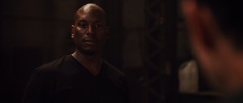 Movie still from “Fast Five” (2011), directed by Justin Lin – A man in a black shirt is standing in a dark room; Close Up shot, Low angle
