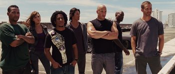 Movie still from “Fast Five” (2011), directed by Justin Lin – A group of men standing next to each other on the street; Medium shot, Low angle