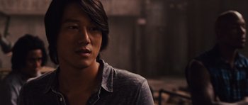 Movie still from “Fast Five” (2011), directed by Justin Lin – A man with long black hair wearing a gray shirt; Close Up shot, Over the shoulder angle
