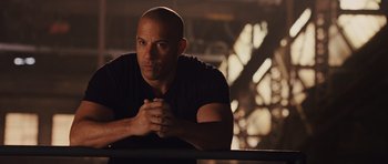 Movie still from “Fast Five” (2011), directed by Justin Lin – A bald man leaning on a railing in front of trees; Close Up shot, Over the shoulder angle