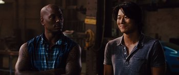 Movie still from “Fast Five” (2011), directed by Justin Lin – A man standing next to a woman in front of a building; Medium shot, Over the shoulder angle
