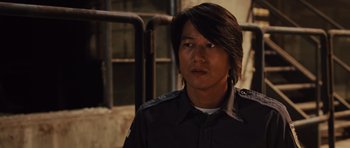 Movie still from “Fast Five” (2011), directed by Justin Lin – A man with long black hair wearing a black shirt; Close Up shot, Over the shoulder angle