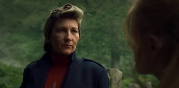 Movie still from “Fate: The Winx Saga” (2021), created by Brian Young – An older woman wearing a red sweater and a blue jacket; Close Up shot, Over the shoulder angle