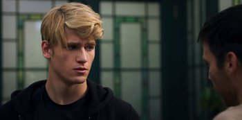 Movie still from “Fate: The Winx Saga” (2021), created by Brian Young – A man with blonde hair and a black hoodie; Close Up shot, Over the shoulder angle