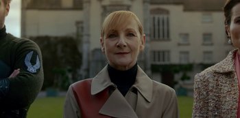 Movie still from “Fate: The Winx Saga” (2021), created by Brian Young – An older woman wearing a trench coat and a black shirt; Close Up shot, Low angle