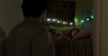 Movie still from “Black Mirror” (2011), created by Charlie Brooker – A young girl laying in a bed with a teddy bear; Medium shot, Over the shoulder angle