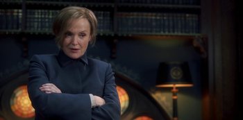 Movie still from “Fate: The Winx Saga” (2021), created by Brian Young – A woman standing in front of a lamp in a room; Medium shot, Over the shoulder angle