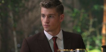 Movie still from “Fate: The Winx Saga” (2021), created by Brian Young – A man in a brown suit and a red tie; Close Up shot, Over the shoulder angle