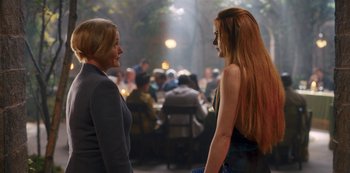 Movie still from “Fate: The Winx Saga” (2021), created by Brian Young – Two women standing next to each other in front of a crowd of diners; Medium shot, Over the shoulder angle