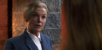 Movie still from “Fate: The Winx Saga” (2021), created by Brian Young – A woman wearing a suit looking into a mirror; Close Up shot, Over the shoulder angle