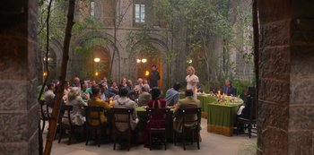 Movie still from “Fate: The Winx Saga” (2021), created by Brian Young – A group of people sitting around a table with food on top of it; Wide shot, High angle