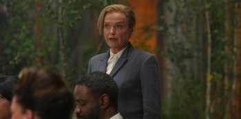 Movie still from “Fate: The Winx Saga” (2021), created by Brian Young – A woman wearing a suit and tie standing in front of a man; Medium shot, Over the shoulder angle