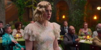 Movie still from “Fate: The Winx Saga” (2021), created by Brian Young – A woman in a white dress standing in front of a crowd; Medium shot, Over the shoulder angle