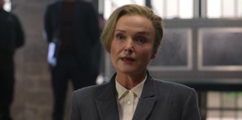 Movie still from “Fate: The Winx Saga” (2021), created by Brian Young – A woman in a gray suit is looking at the camera; Close Up shot, Over the shoulder angle