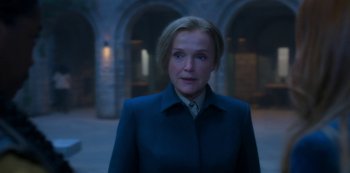Movie still from “Fate: The Winx Saga” (2021), created by Brian Young – A woman wearing a blue coat standing in front of an archway; Close Up shot, Over the shoulder angle