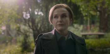 Movie still from “Fate: The Winx Saga” (2021), created by Brian Young – A woman with short blonde hair wearing a gray coat; Close Up shot, Over the shoulder angle