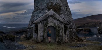 Movie still from “Fate: The Winx Saga” (2021), created by Brian Young – A woman standing in front of a stone building; Extreme Wide shot, Low angle
