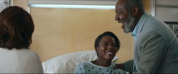 Movie still from “Fatherhood” (2021), directed by Paul Weitz – A man and a woman in a hospital bed smiling; Medium shot, Over the shoulder angle