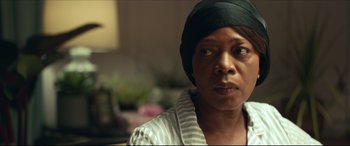 Movie still from “Fatherhood” (2021), directed by Paul Weitz – An older woman wearing a black hat looking at the camera; Close Up shot, Over the shoulder angle