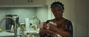 Movie still from “Fatherhood” (2021), directed by Paul Weitz – A woman holding a baby in her arms in a kitchen; Close Up shot, Over the shoulder angle