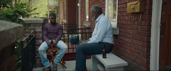 Movie still from “Fatherhood” (2021), directed by Paul Weitz – Two men sitting on a bench on a porch; Wide shot, Over the shoulder angle