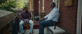 Movie still from “Fatherhood” (2021), directed by Paul Weitz – Two men sitting on a bench talking to each other; Wide shot, Over the shoulder angle
