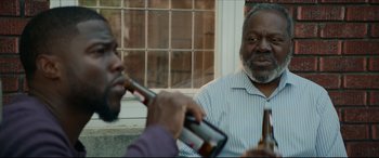 Movie still from “Fatherhood” (2021), directed by Paul Weitz – Two men sitting on a bench drinking beer; Close Up shot, Over the shoulder angle