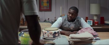 Movie still from “Fatherhood” (2021), directed by Paul Weitz – A man sitting at a table with a bowl of food in front of him; Medium shot, Over the shoulder angle