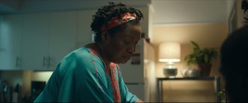 Movie still from “Fatherhood” (2021), directed by Paul Weitz – An older black woman wearing a blue shirt and a red headband; Close Up shot, Over the shoulder angle
