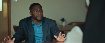 Movie still from “Fatherhood” (2021), directed by Paul Weitz – A man sitting at a table talking to another man; Medium shot, Over the shoulder angle