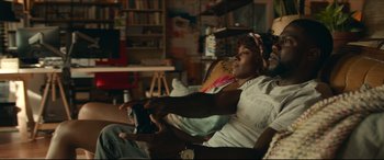 Movie still from “Fatherhood” (2021), directed by Paul Weitz – A woman sitting in a chair holding a remote control; Close Up shot, Over the shoulder angle