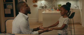 Movie still from “Fatherhood” (2021), directed by Paul Weitz – A man and a woman holding hands in a kitchen; Medium shot, Over the shoulder angle