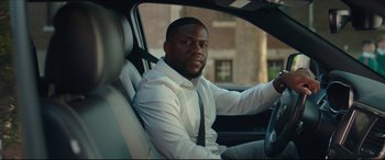 Movie still from “Fatherhood” (2021), directed by Paul Weitz – A man sitting in the driver's seat of a car; Medium shot, Over the shoulder angle