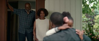 Movie still from “Fatherhood” (2021), directed by Paul Weitz – A woman standing in front of a mirror while a man takes a picture of her; Medium shot, Over the shoulder angle