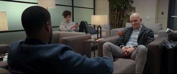 Movie still from “Fatherhood” (2021), directed by Paul Weitz – A group of people sitting around a room on couches; Wide shot, Over the shoulder angle