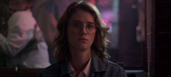 Movie still from “Black Mirror” (2011), created by Charlie Brooker – A woman with glasses is looking straight ahead; Close Up shot, Over the shoulder angle