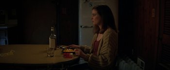 Movie still from “Fear Street: Part Two - 1978” (2021), directed by Leigh Janiak – A woman sitting at a table playing a video game; Medium shot, Over the shoulder angle