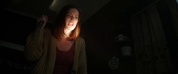 Movie still from “Fear Street: Part Two - 1978” (2021), directed by Leigh Janiak – A woman standing in a dark room with her mouth wide open; Medium shot, Low angle