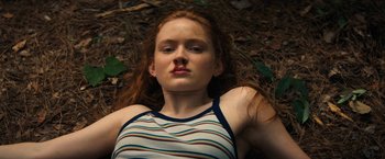Movie still from “Fear Street: Part Two - 1978” (2021), directed by Leigh Janiak – A young woman laying on the ground in a forest; Close Up shot, High angle