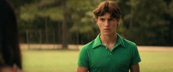 Movie still from “Fear Street: Part Two - 1978” (2021), directed by Leigh Janiak – A young man in a green polo shirt looks into the distance; Medium shot, Over the shoulder angle