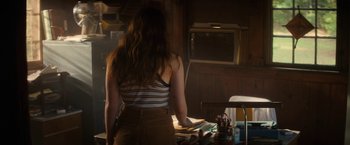 Movie still from “Fear Street: Part Two - 1978” (2021), directed by Leigh Janiak – A woman standing in front of a desk with papers on top of it; Medium shot, Over the shoulder angle