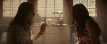 Movie still from “Fear Street: Part Two - 1978” (2021), directed by Leigh Janiak – Two women in a kitchen one is holding a camera; Close Up shot, Over the shoulder angle