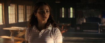 Movie still from “Fear Street: Part Two - 1978” (2021), directed by Leigh Janiak – A woman in a striped shirt is standing in a room; Close Up shot, Over the shoulder angle