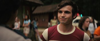 Movie still from “Fear Street: Part Two - 1978” (2021), directed by Leigh Janiak – A man in a red and white striped shirt looks to his left; Close Up shot, Over the shoulder angle