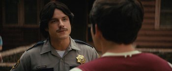 Movie still from “Fear Street: Part Two - 1978” (2021), directed by Leigh Janiak – A man in a uniform talking to another man in front of a mirror; Close Up shot, Over the shoulder angle