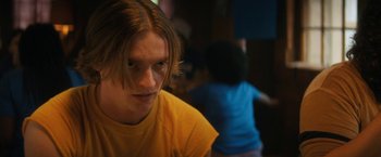 Movie still from “Fear Street: Part Two - 1978” (2021), directed by Leigh Janiak – A young man in a yellow t - shirt looks at the camera; Close Up shot, Low angle