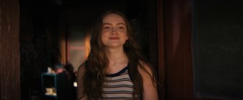 Movie still from “Fear Street: Part Two - 1978” (2021), directed by Leigh Janiak – A young woman with long hair is smiling for the camera; Close Up shot, Over the shoulder angle