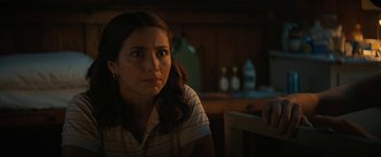 Movie still from “Fear Street: Part Two - 1978” (2021), directed by Leigh Janiak – A woman sitting at a table in a dark room; Close Up shot, Over the shoulder angle